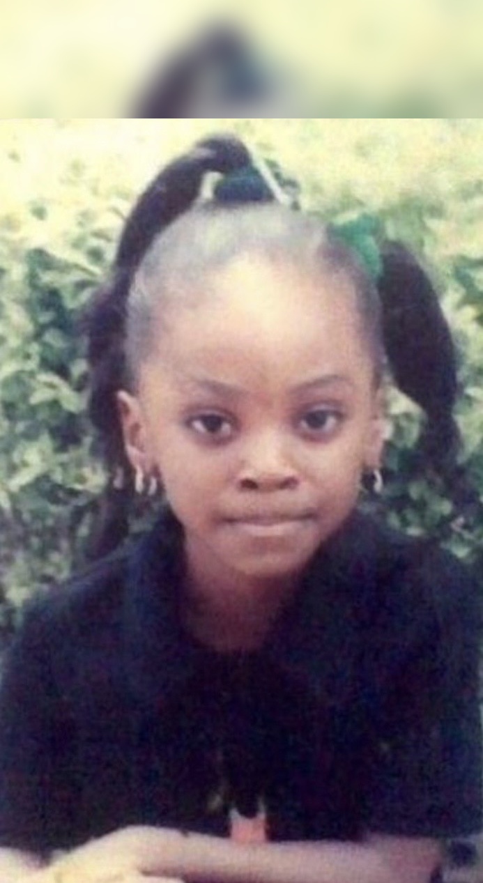 Daisy as a young girl, hair in two ponytails with a green ribbon